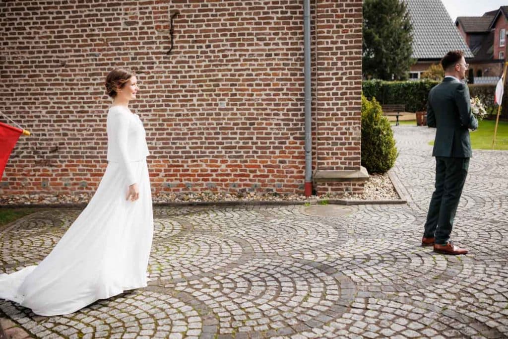First Look. Ein Brautpaar in Wesel trifft sich zum ersten Mal vor der kirchlichen Trauung, festgehalten von einem Hochzeitsfotografen in Wesel