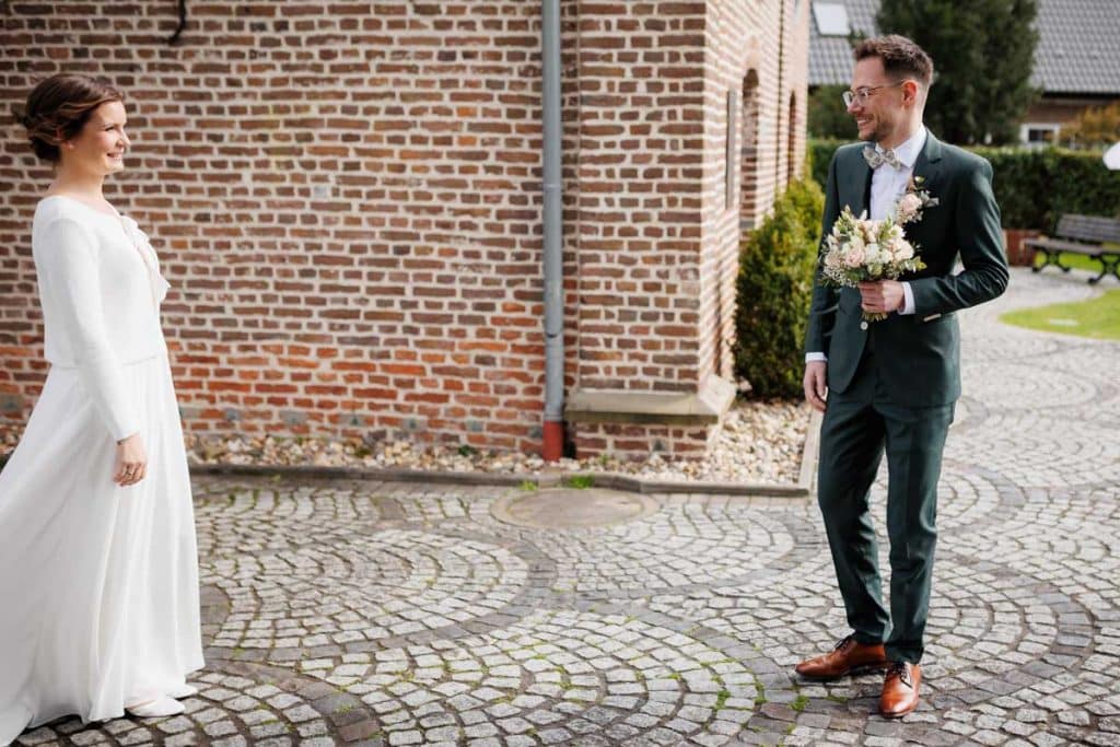 First Look. Ein Brautpaar in Wesel trifft sich zum ersten Mal vor der kirchlichen Trauung, festgehalten von einem Hochzeitsfotografen in Wesel