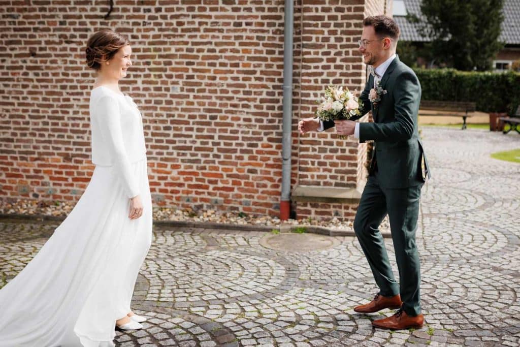 First Look. Ein Brautpaar in Wesel trifft sich zum ersten Mal vor der kirchlichen Trauung, festgehalten von einem Hochzeitsfotografen in Wesel