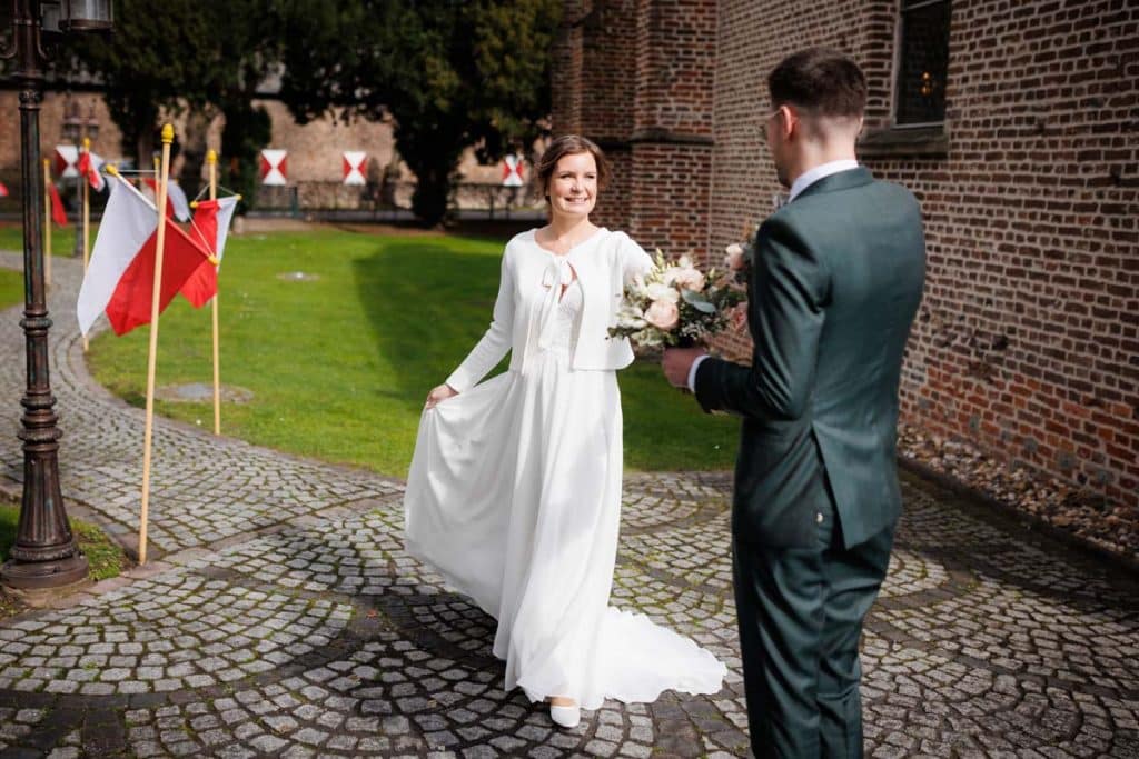 First Look. Ein Brautpaar in Wesel trifft sich zum ersten Mal vor der kirchlichen Trauung, festgehalten von einem Hochzeitsfotografen in Wesel