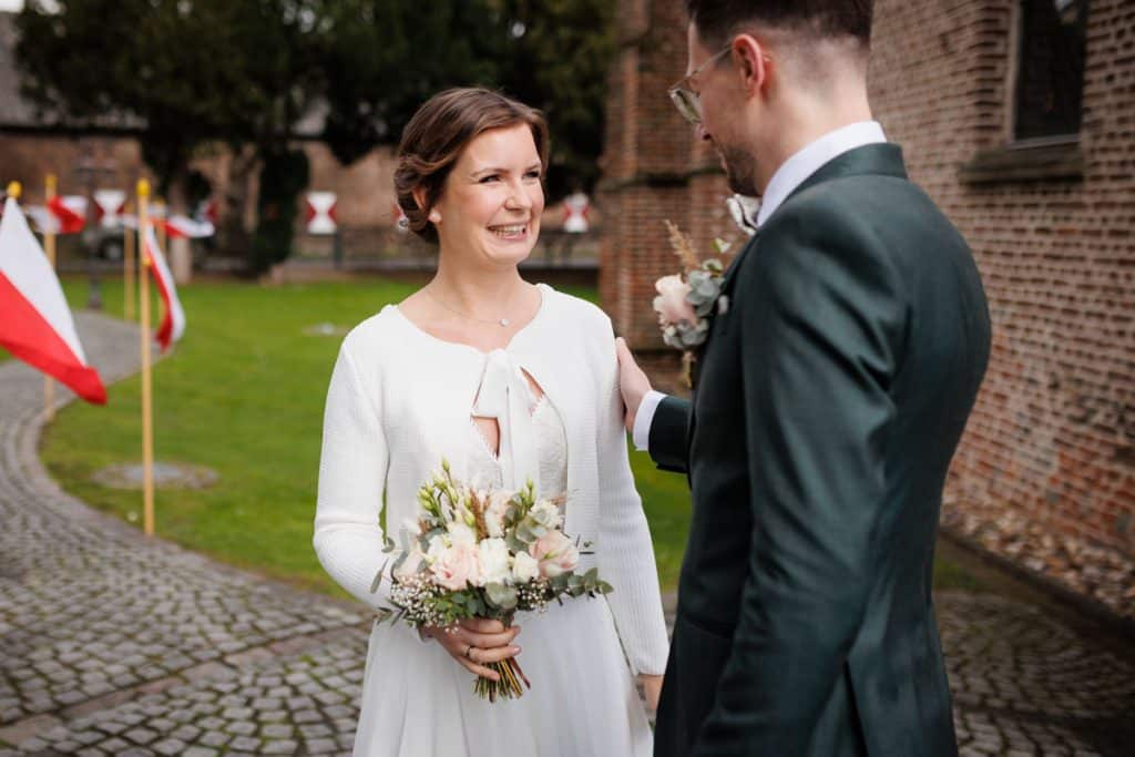 First Look. Ein Brautpaar in Wesel trifft sich zum ersten Mal vor der kirchlichen Trauung, festgehalten von einem Hochzeitsfotografen in Wesel
