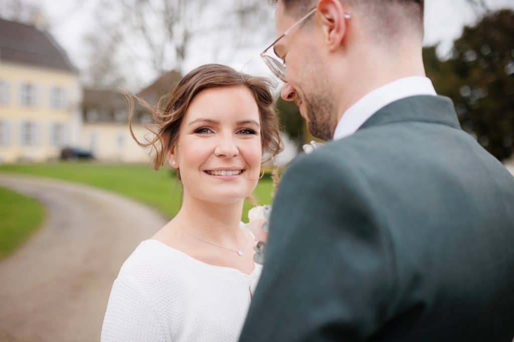 Romantisches Hochzeitsfotoshooting am Landhaus Ridder in Wesel-Hamminkeln: Das Brautpaar posiert in der idyllischen Parkanlage der beliebten Hochzeitslocation. Die Braut trägt ein elegantes Spitzenkleid, der Bräutigam einen festlichen Anzug. Dieses Foto zeigt die natürliche und authentische Hochzeitsfotografie beim Landhaus Ridder in Wesel-Hamminkeln