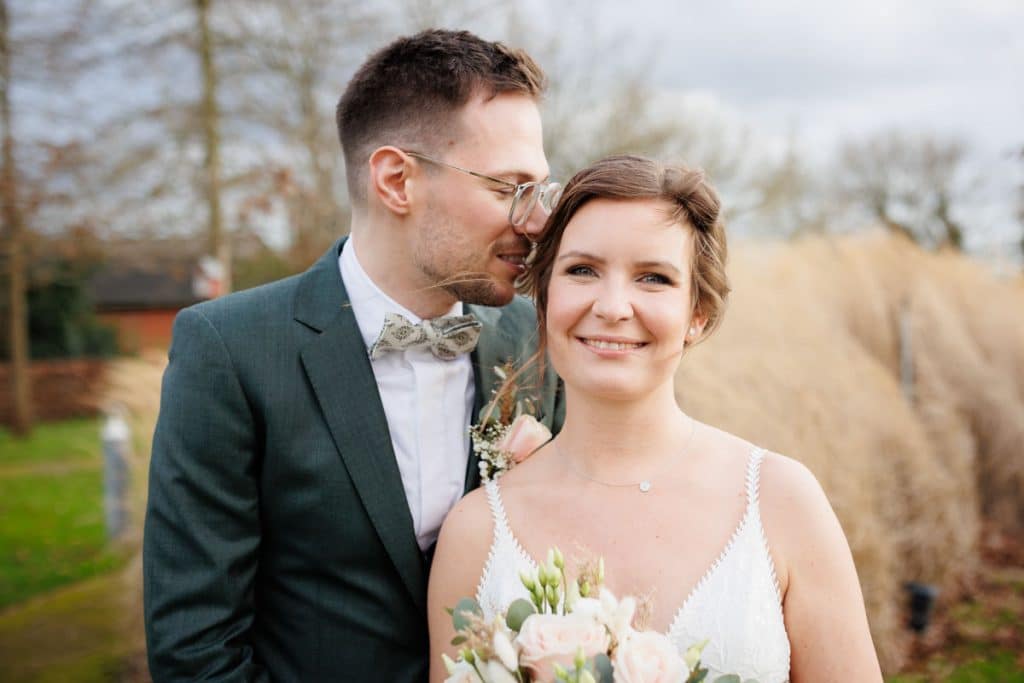 Romantisches Hochzeitsfotoshooting am Landhaus Ridder in Wesel-Hamminkeln: Das Brautpaar posiert in der idyllischen Parkanlage der beliebten Hochzeitslocation. Die Braut trägt ein elegantes Spitzenkleid, der Bräutigam einen festlichen Anzug. Dieses Foto zeigt die natürliche und authentische Hochzeitsfotografie beim Landhaus Ridder in Wesel-Hamminkeln