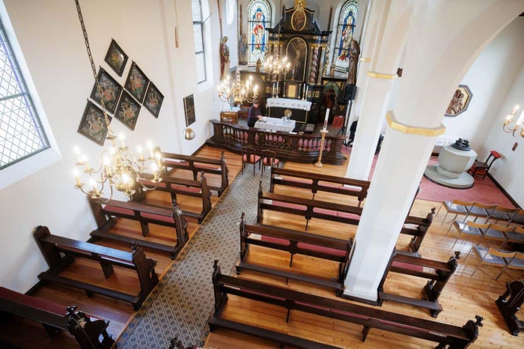 Emotionaler Moment bei der kirchlichen Trauung in Wesel: Das Brautpaar steht gemeinsam am Altar, die Braut im weißen Spitzenkleid mit Schleier, der Bräutigam im eleganten Anzug. Gäste verfolgen die Zeremonie in der Kirche aufmerksam. Dieses authentische Hochzeitsfoto hält die besonderen Augenblicke fest und zeigt die lebendige Hochzeitsfotografie in Wesel.