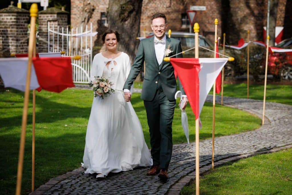 Emotionaler Moment bei der kirchlichen Trauung in Wesel: Das Brautpaar steht gemeinsam am Altar, die Braut im weißen Spitzenkleid mit Schleier, der Bräutigam im eleganten Anzug. Gäste verfolgen die Zeremonie in der Kirche aufmerksam. Dieses authentische Hochzeitsfoto hält die besonderen Augenblicke fest und zeigt die lebendige Hochzeitsfotografie in Wesel.