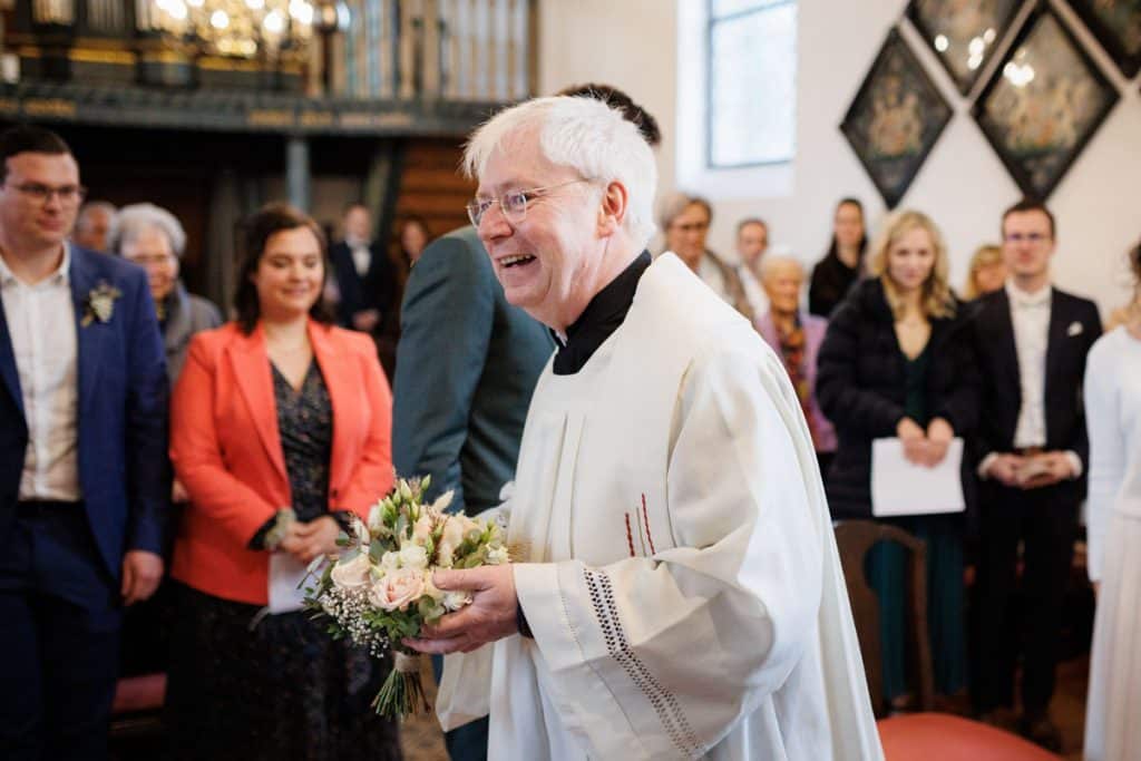 Emotionaler Moment bei der kirchlichen Trauung in Wesel: Das Brautpaar steht gemeinsam am Altar, die Braut im weißen Spitzenkleid mit Schleier, der Bräutigam im eleganten Anzug. Gäste verfolgen die Zeremonie in der Kirche aufmerksam. Dieses authentische Hochzeitsfoto hält die besonderen Augenblicke fest und zeigt die lebendige Hochzeitsfotografie in Wesel.