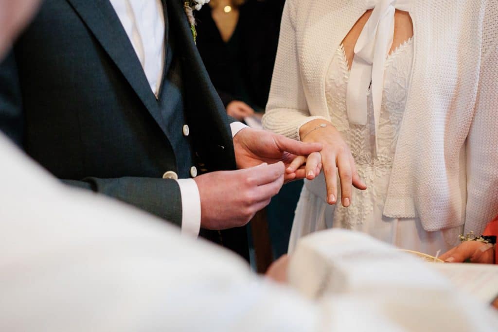 Emotionaler Moment bei der kirchlichen Trauung in Wesel: Das Brautpaar steht gemeinsam am Altar, die Braut im weißen Spitzenkleid mit Schleier, der Bräutigam im eleganten Anzug. Gäste verfolgen die Zeremonie in der Kirche aufmerksam. Dieses authentische Hochzeitsfoto hält die besonderen Augenblicke fest und zeigt die lebendige Hochzeitsfotografie in Wesel.