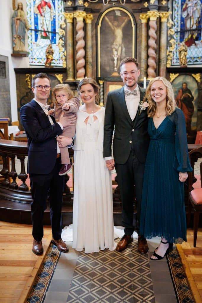 Emotionaler Moment bei der kirchlichen Trauung in Wesel: Das Brautpaar steht gemeinsam am Altar, die Braut im weißen Spitzenkleid mit Schleier, der Bräutigam im eleganten Anzug. Gäste verfolgen die Zeremonie in der Kirche aufmerksam. Dieses authentische Hochzeitsfoto hält die besonderen Augenblicke fest und zeigt die lebendige Hochzeitsfotografie in Wesel.