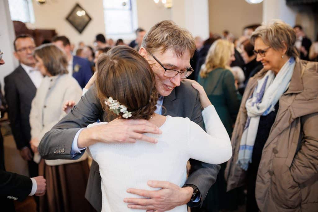 Emotionaler Moment bei der kirchlichen Trauung in Wesel: Das Brautpaar steht gemeinsam am Altar, die Braut im weißen Spitzenkleid mit Schleier, der Bräutigam im eleganten Anzug. Gäste verfolgen die Zeremonie in der Kirche aufmerksam. Dieses authentische Hochzeitsfoto hält die besonderen Augenblicke fest und zeigt die lebendige Hochzeitsfotografie in Wesel.