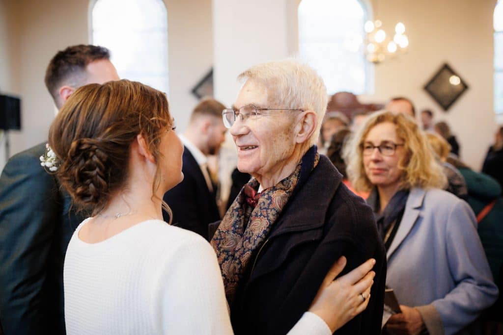 Emotionaler Moment bei der kirchlichen Trauung in Wesel: Das Brautpaar steht gemeinsam am Altar, die Braut im weißen Spitzenkleid mit Schleier, der Bräutigam im eleganten Anzug. Gäste verfolgen die Zeremonie in der Kirche aufmerksam. Dieses authentische Hochzeitsfoto hält die besonderen Augenblicke fest und zeigt die lebendige Hochzeitsfotografie in Wesel.