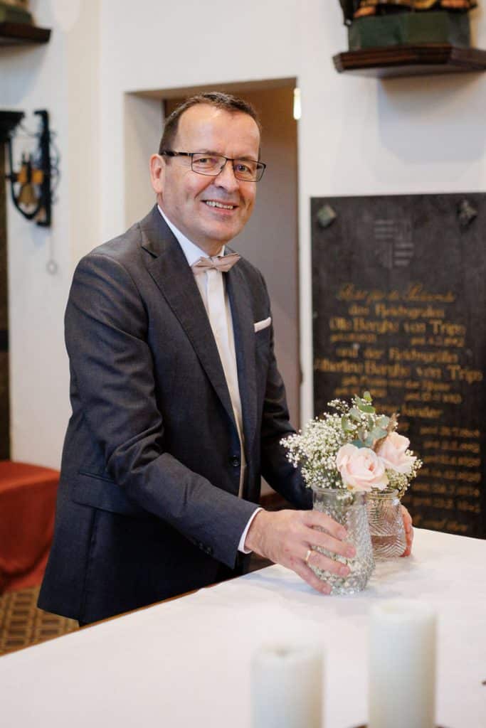 Emotionaler Moment bei der kirchlichen Trauung in Wesel: Das Brautpaar steht gemeinsam am Altar, die Braut im weißen Spitzenkleid mit Schleier, der Bräutigam im eleganten Anzug. Gäste verfolgen die Zeremonie in der Kirche aufmerksam. Dieses authentische Hochzeitsfoto hält die besonderen Augenblicke fest und zeigt die lebendige Hochzeitsfotografie in Wesel.
