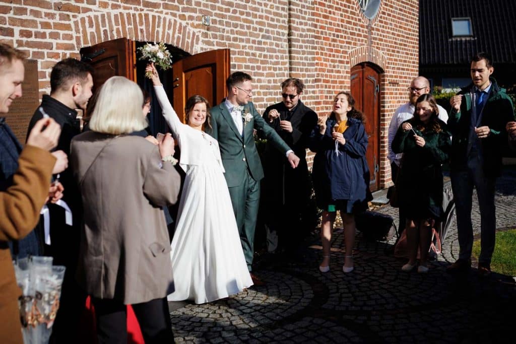 Emotionaler Moment bei der kirchlichen Trauung in Wesel: Das Brautpaar steht gemeinsam am Altar, die Braut im weißen Spitzenkleid mit Schleier, der Bräutigam im eleganten Anzug. Gäste verfolgen die Zeremonie in der Kirche aufmerksam. Dieses authentische Hochzeitsfoto hält die besonderen Augenblicke fest und zeigt die lebendige Hochzeitsfotografie in Wesel.