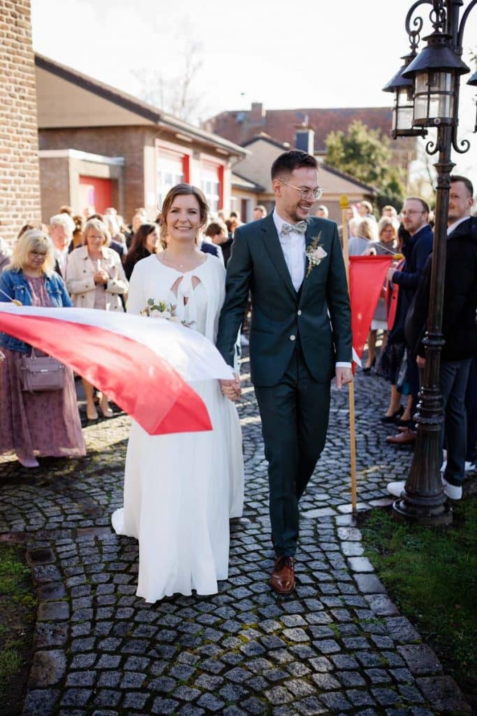 Emotionaler Moment bei der kirchlichen Trauung in Wesel: Das Brautpaar steht gemeinsam am Altar, die Braut im weißen Spitzenkleid mit Schleier, der Bräutigam im eleganten Anzug. Gäste verfolgen die Zeremonie in der Kirche aufmerksam. Dieses authentische Hochzeitsfoto hält die besonderen Augenblicke fest und zeigt die lebendige Hochzeitsfotografie in Wesel.