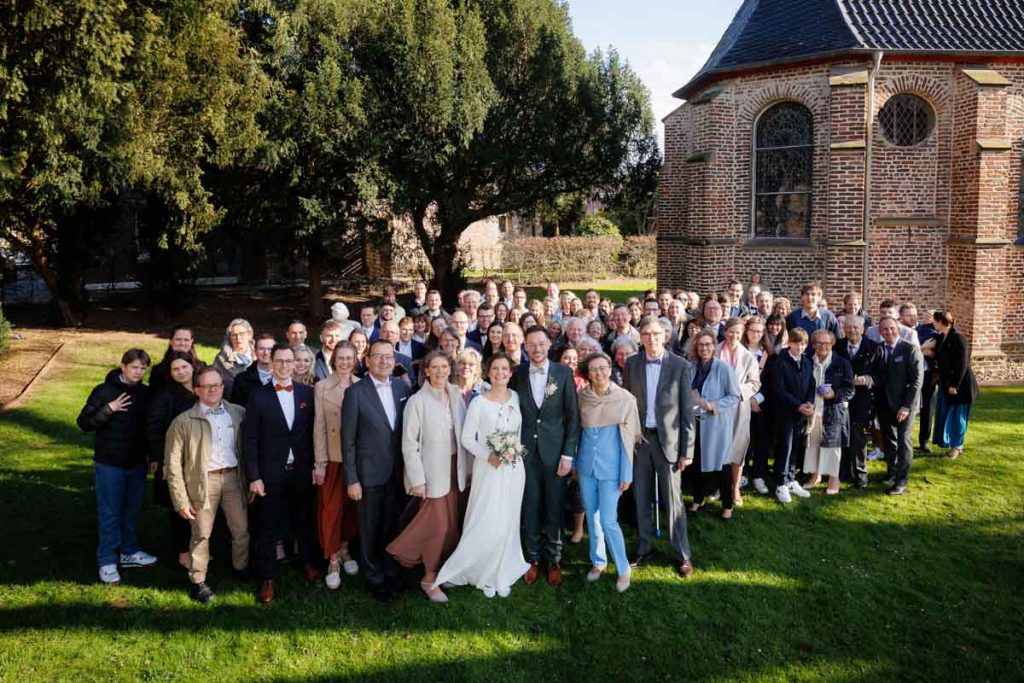 Emotionaler Moment bei der kirchlichen Trauung in Wesel: Das Brautpaar steht gemeinsam am Altar, die Braut im weißen Spitzenkleid mit Schleier, der Bräutigam im eleganten Anzug. Gäste verfolgen die Zeremonie in der Kirche aufmerksam. Dieses authentische Hochzeitsfoto hält die besonderen Augenblicke fest und zeigt die lebendige Hochzeitsfotografie in Wesel.