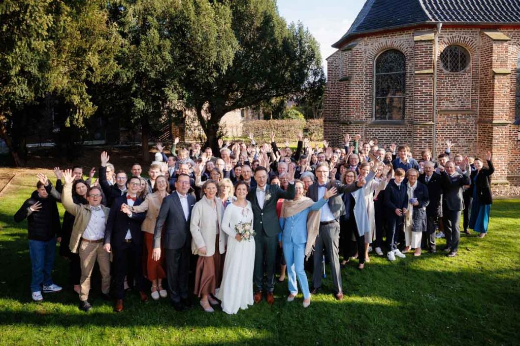 Emotionaler Moment bei der kirchlichen Trauung in Wesel: Das Brautpaar steht gemeinsam am Altar, die Braut im weißen Spitzenkleid mit Schleier, der Bräutigam im eleganten Anzug. Gäste verfolgen die Zeremonie in der Kirche aufmerksam. Dieses authentische Hochzeitsfoto hält die besonderen Augenblicke fest und zeigt die lebendige Hochzeitsfotografie in Wesel.