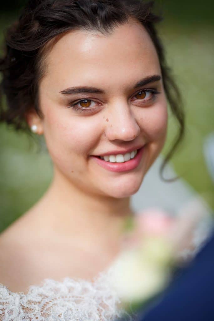 Romantisches Brautpaarshooting im Kurpark in Xanten: Die Braut im eleganten Spitzenkleid und der Bräutigam im festlichen Anzug spazieren Hand in Hand durch die Parkanlage. Sonnenlicht, grüne Bäume und Blumenrabatten schaffen eine idyllische Kulisse. Dieses Foto zeigt die natürliche und moderne Hochzeitsfotografie vom Hochzeitsfotograf Xanten.