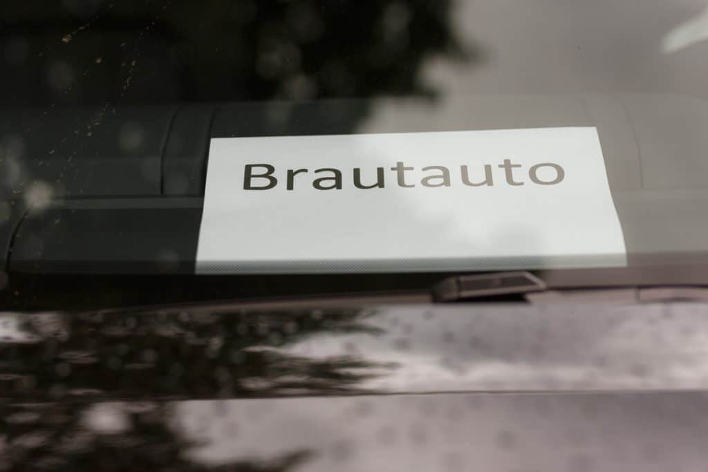 Romantisches Brautpaarshooting im Kurpark in Xanten: Die Braut im eleganten Spitzenkleid und der Bräutigam im festlichen Anzug spazieren Hand in Hand durch die Parkanlage. Sonnenlicht, grüne Bäume und Blumenrabatten schaffen eine idyllische Kulisse. Dieses Foto zeigt die natürliche und moderne Hochzeitsfotografie vom Hochzeitsfotograf Xanten.
