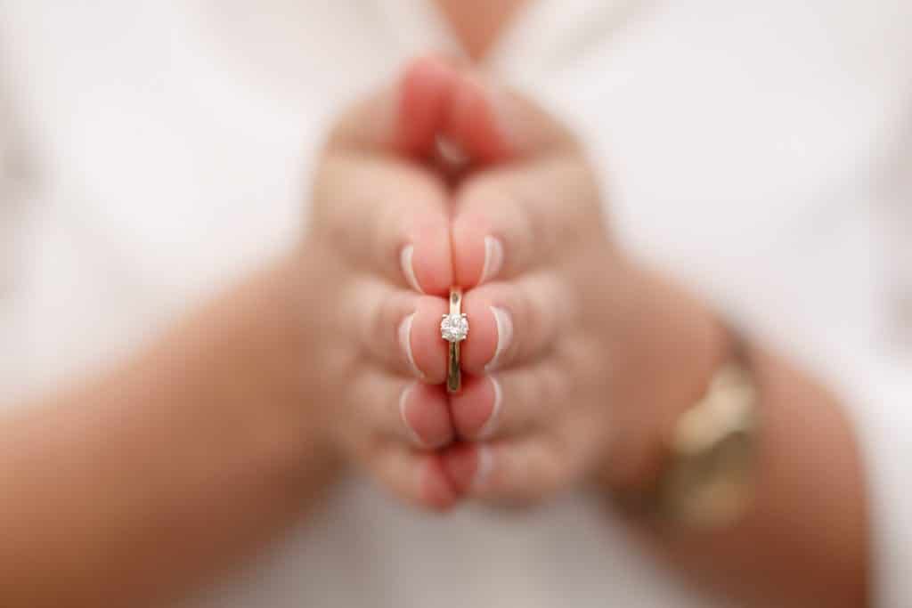 Makroaufnahme eines funkelnden Verlobungsrings: Der Ring mit Solitärdiamant wird in den Händen der zukünftigen Braut gehalten, die Fingernägel sind elegant manikürt. Dieses intime Detailfoto ist ein Highlight jedes Verlobungsshootings, festgehalten vom Hochzeitsfotograf Duisburg, Wesel und Dinslaken.