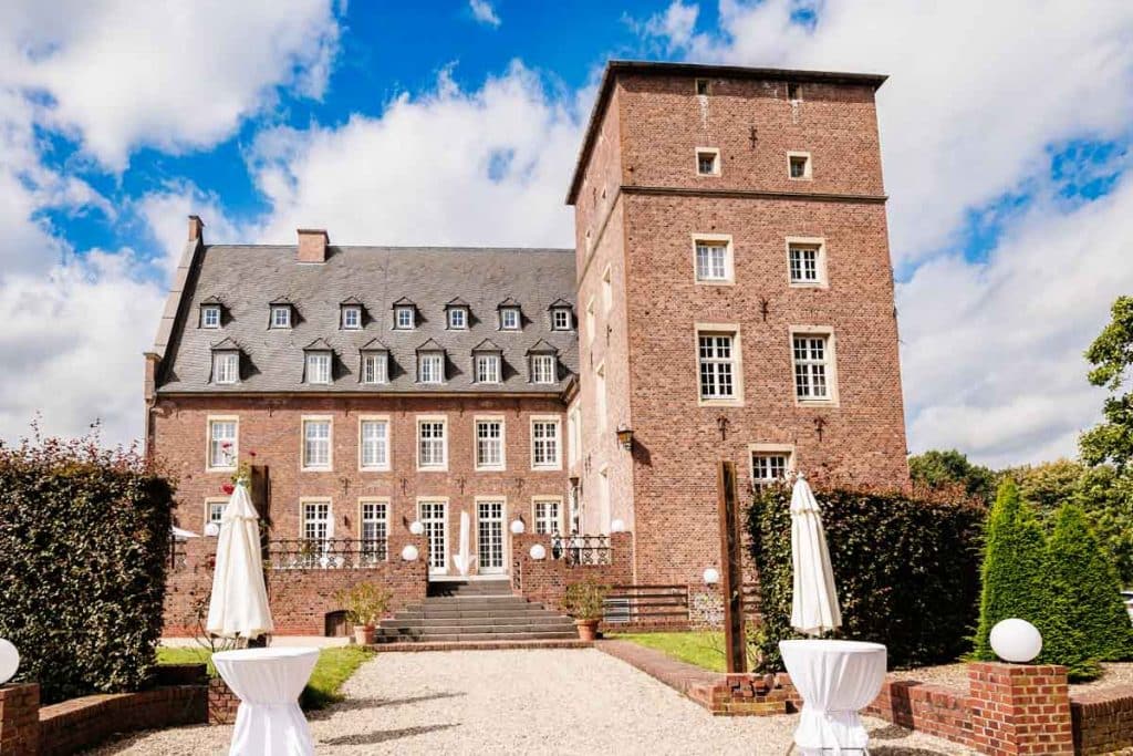 Emotionaler First Look von Braut und Bräutigam auf Schloss Diersfordt in Wesel: Der Bräutigam sieht seine Braut zum ersten Mal im weißen Kleid. Die historische Schlosskulisse sorgt für eine romantische Atmosphäre. Festgehalten vom Hochzeitsfotograf Wesel.