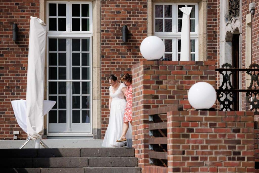 Emotionaler First Look von Braut und Bräutigam auf Schloss Diersfordt in Wesel: Der Bräutigam sieht seine Braut zum ersten Mal im weißen Kleid. Die historische Schlosskulisse sorgt für eine romantische Atmosphäre. Festgehalten vom Hochzeitsfotograf Wesel.