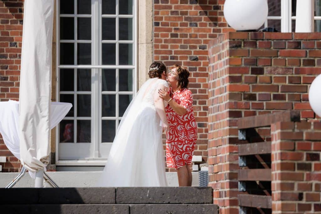 Emotionaler First Look von Braut und Bräutigam auf Schloss Diersfordt in Wesel: Der Bräutigam sieht seine Braut zum ersten Mal im weißen Kleid. Die historische Schlosskulisse sorgt für eine romantische Atmosphäre. Festgehalten vom Hochzeitsfotograf Wesel.