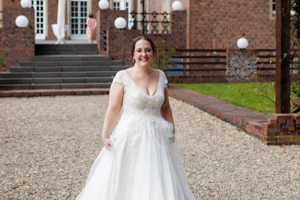 Emotionaler First Look von Braut und Bräutigam auf Schloss Diersfordt in Wesel: Der Bräutigam sieht seine Braut zum ersten Mal im weißen Kleid. Die historische Schlosskulisse sorgt für eine romantische Atmosphäre. Festgehalten vom Hochzeitsfotograf Wesel.