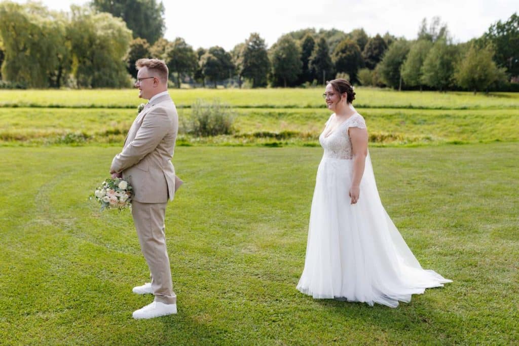 Emotionaler First Look von Braut und Bräutigam auf Schloss Diersfordt in Wesel: Der Bräutigam sieht seine Braut zum ersten Mal im weißen Kleid. Die historische Schlosskulisse sorgt für eine romantische Atmosphäre. Festgehalten vom Hochzeitsfotograf Wesel.