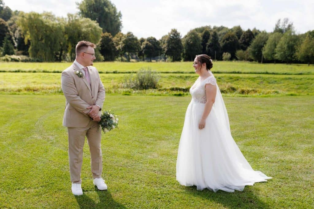 Emotionaler First Look von Braut und Bräutigam auf Schloss Diersfordt in Wesel: Der Bräutigam sieht seine Braut zum ersten Mal im weißen Kleid. Die historische Schlosskulisse sorgt für eine romantische Atmosphäre. Festgehalten vom Hochzeitsfotograf Wesel.