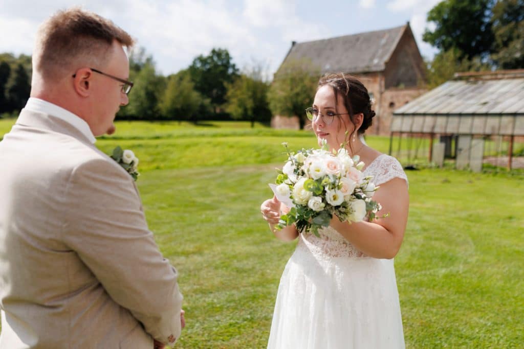 Emotionaler First Look von Braut und Bräutigam auf Schloss Diersfordt in Wesel: Der Bräutigam sieht seine Braut zum ersten Mal im weißen Kleid. Die historische Schlosskulisse sorgt für eine romantische Atmosphäre. Festgehalten vom Hochzeitsfotograf Wesel.