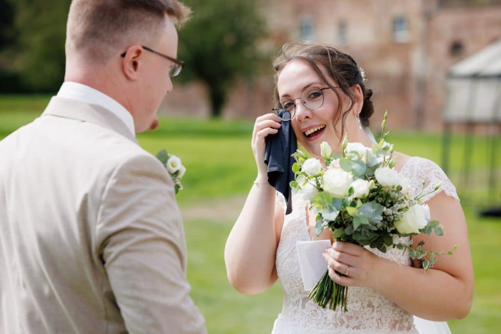 Emotionaler First Look von Braut und Bräutigam auf Schloss Diersfordt in Wesel: Der Bräutigam sieht seine Braut zum ersten Mal im weißen Kleid. Die historische Schlosskulisse sorgt für eine romantische Atmosphäre. Festgehalten vom Hochzeitsfotograf Wesel.