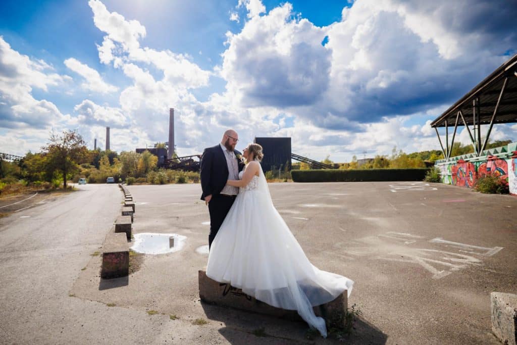 Fotoshooting im Landschaftspark Duisburg Nord: Das Brautpaar posiert in der einzigartigen Industriekulisse zwischen alten Stahlkonstruktionen und grüner Natur. Kreative und emotionale Hochzeitsfotos voller Kontraste, festgehalten vom Hochzeitsfotograf Duisburg.