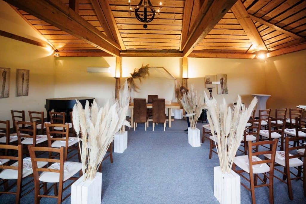 Emotionale freie Trauung im Innenbereich des Landgut Hochwald in Sonsbeck: Das Brautpaar gibt sich vor Familie und Freunden das Ja-Wort. Kerzen, Blumenarrangements und stimmungsvolles Licht sorgen für eine romantische Atmosphäre. Besondere Augenblicke festgehalten vom Hochzeitsfotograf Niederrhein.