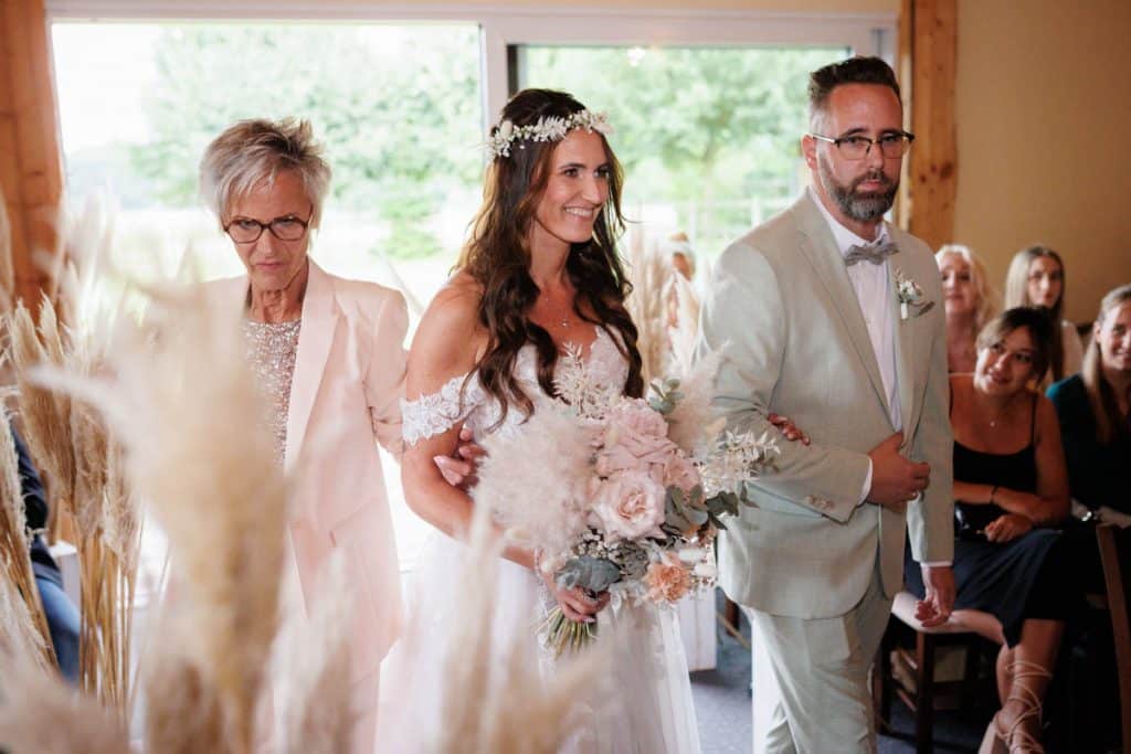 Emotionale freie Trauung im Innenbereich des Landgut Hochwald in Sonsbeck: Das Brautpaar gibt sich vor Familie und Freunden das Ja-Wort. Kerzen, Blumenarrangements und stimmungsvolles Licht sorgen für eine romantische Atmosphäre. Besondere Augenblicke festgehalten vom Hochzeitsfotograf Niederrhein.