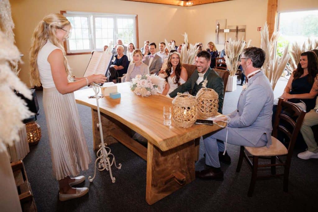 Emotionale freie Trauung im Innenbereich des Landgut Hochwald in Sonsbeck: Das Brautpaar gibt sich vor Familie und Freunden das Ja-Wort. Kerzen, Blumenarrangements und stimmungsvolles Licht sorgen für eine romantische Atmosphäre. Besondere Augenblicke festgehalten vom Hochzeitsfotograf Niederrhein.