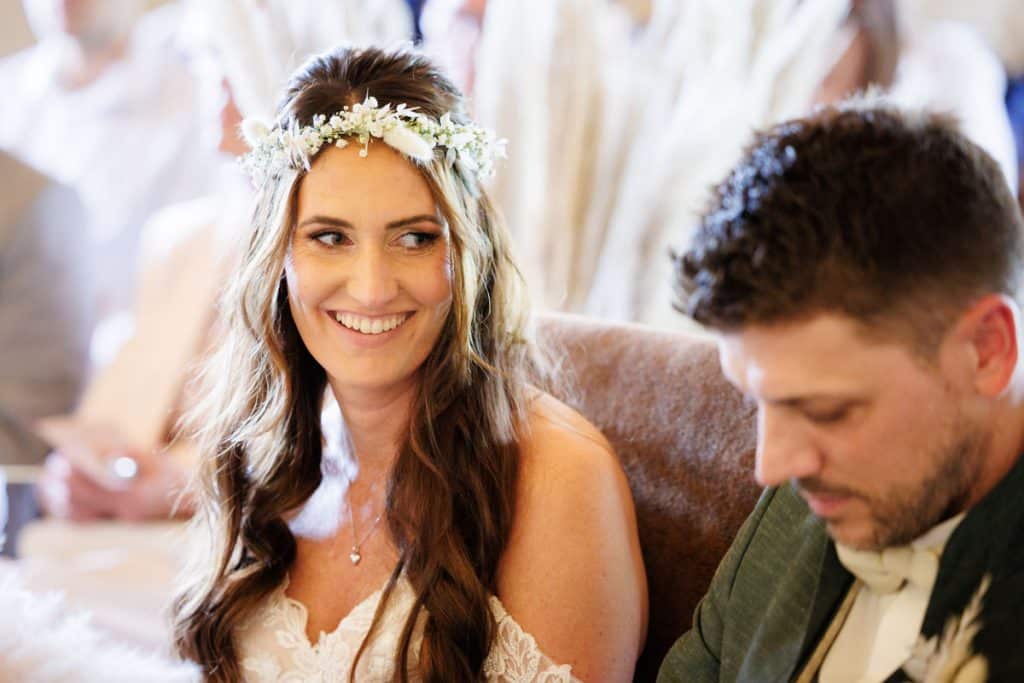 Emotionale freie Trauung im Innenbereich des Landgut Hochwald in Sonsbeck: Das Brautpaar gibt sich vor Familie und Freunden das Ja-Wort. Kerzen, Blumenarrangements und stimmungsvolles Licht sorgen für eine romantische Atmosphäre. Besondere Augenblicke festgehalten vom Hochzeitsfotograf Niederrhein.