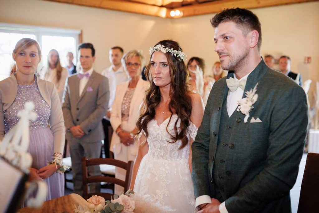 Emotionale freie Trauung im Innenbereich des Landgut Hochwald in Sonsbeck: Das Brautpaar gibt sich vor Familie und Freunden das Ja-Wort. Kerzen, Blumenarrangements und stimmungsvolles Licht sorgen für eine romantische Atmosphäre. Besondere Augenblicke festgehalten vom Hochzeitsfotograf Niederrhein.