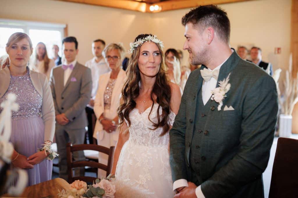 Emotionale freie Trauung im Innenbereich des Landgut Hochwald in Sonsbeck: Das Brautpaar gibt sich vor Familie und Freunden das Ja-Wort. Kerzen, Blumenarrangements und stimmungsvolles Licht sorgen für eine romantische Atmosphäre. Besondere Augenblicke festgehalten vom Hochzeitsfotograf Niederrhein.