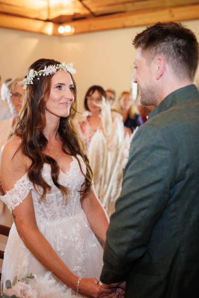 Emotionale freie Trauung im Innenbereich des Landgut Hochwald in Sonsbeck: Das Brautpaar gibt sich vor Familie und Freunden das Ja-Wort. Kerzen, Blumenarrangements und stimmungsvolles Licht sorgen für eine romantische Atmosphäre. Besondere Augenblicke festgehalten vom Hochzeitsfotograf Niederrhein.