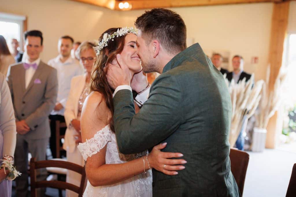 Emotionale freie Trauung im Innenbereich des Landgut Hochwald in Sonsbeck: Das Brautpaar gibt sich vor Familie und Freunden das Ja-Wort. Kerzen, Blumenarrangements und stimmungsvolles Licht sorgen für eine romantische Atmosphäre. Besondere Augenblicke festgehalten vom Hochzeitsfotograf Niederrhein.