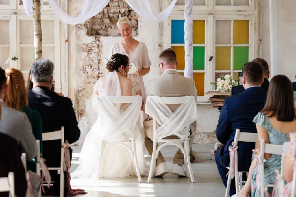 Freie Trauung in der stilvollen Orangerie von Schloss Diersfordt in Wesel: Das Brautpaar gibt sich vor Familie und Freunden das Ja-Wort in eleganter, lichtdurchfluteter Umgebung. Blumendekoration, romantisches Ambiente und die besondere Location machen diesen Moment einzigartig. Festgehalten vom Hochzeitsfotograf Wesel.