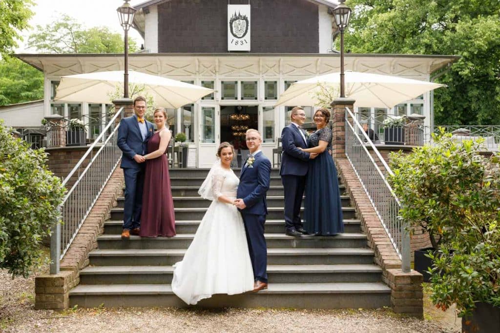 Fröhliche Gruppenfotos nach der Hochzeit in Xanten: Das Brautpaar posiert mit Familie und Freunden vor der Kirche. Lächelnde Gesichter, elegante Outfits und die festliche Stimmung machen die Gruppenfotos zu einer bleibenden Erinnerung. Fotografiert vom Hochzeitsfotograf Xanten.