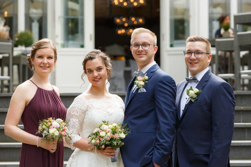 Fröhliche Gruppenfotos nach der Hochzeit in Xanten: Das Brautpaar posiert mit Familie und Freunden vor der Kirche. Lächelnde Gesichter, elegante Outfits und die festliche Stimmung machen die Gruppenfotos zu einer bleibenden Erinnerung. Fotografiert vom Hochzeitsfotograf Xanten.