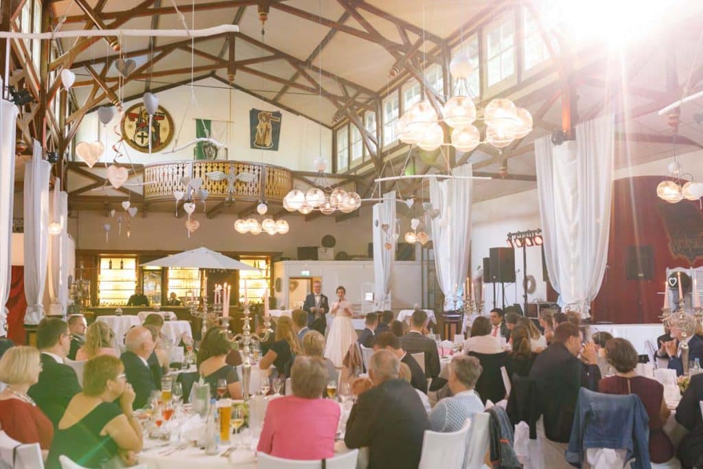 Stimmungsvolle Hochzeitsfeier im Alten Schützenhaus in Xanten: Das Brautpaar tanzt ausgelassen mit Familie und Freunden. Die festlich geschmückte Location, lachende Gäste und Musik schaffen eine lebendige Atmosphäre voller Emotionen. Dieses Foto zeigt die authentische Hochzeitsreportage vom Hochzeitsfotograf Xanten.