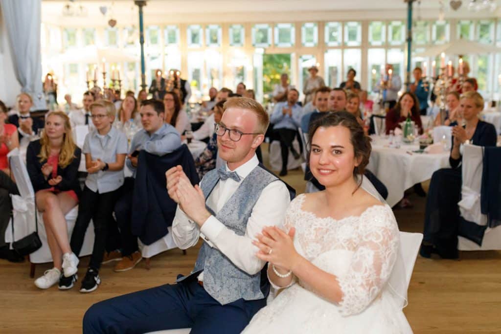 Stimmungsvolle Hochzeitsfeier im Alten Schützenhaus in Xanten: Das Brautpaar tanzt ausgelassen mit Familie und Freunden. Die festlich geschmückte Location, lachende Gäste und Musik schaffen eine lebendige Atmosphäre voller Emotionen. Dieses Foto zeigt die authentische Hochzeitsreportage vom Hochzeitsfotograf Xanten.