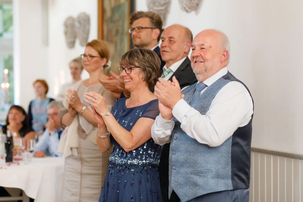 Stimmungsvolle Hochzeitsfeier im Alten Schützenhaus in Xanten: Das Brautpaar tanzt ausgelassen mit Familie und Freunden. Die festlich geschmückte Location, lachende Gäste und Musik schaffen eine lebendige Atmosphäre voller Emotionen. Dieses Foto zeigt die authentische Hochzeitsreportage vom Hochzeitsfotograf Xanten.