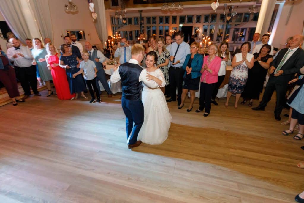 Stimmungsvolle Hochzeitsfeier im Alten Schützenhaus in Xanten: Das Brautpaar tanzt ausgelassen mit Familie und Freunden. Die festlich geschmückte Location, lachende Gäste und Musik schaffen eine lebendige Atmosphäre voller Emotionen. Dieses Foto zeigt die authentische Hochzeitsreportage vom Hochzeitsfotograf Xanten.
