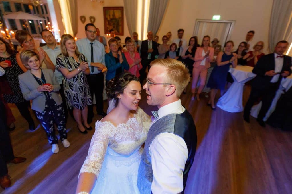 Stimmungsvolle Hochzeitsfeier im Alten Schützenhaus in Xanten: Das Brautpaar tanzt ausgelassen mit Familie und Freunden. Die festlich geschmückte Location, lachende Gäste und Musik schaffen eine lebendige Atmosphäre voller Emotionen. Dieses Foto zeigt die authentische Hochzeitsreportage vom Hochzeitsfotograf Xanten.