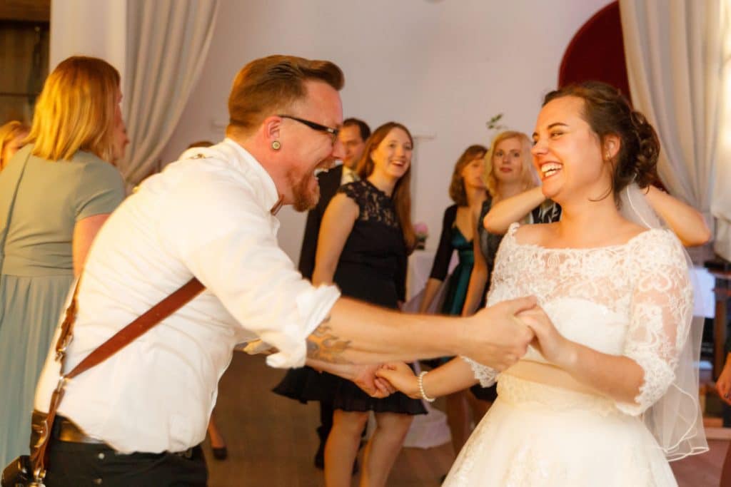 Stimmungsvolle Hochzeitsfeier im Alten Schützenhaus in Xanten: Das Brautpaar tanzt ausgelassen mit Familie und Freunden. Die festlich geschmückte Location, lachende Gäste und Musik schaffen eine lebendige Atmosphäre voller Emotionen. Dieses Foto zeigt die authentische Hochzeitsreportage vom Hochzeitsfotograf Xanten.