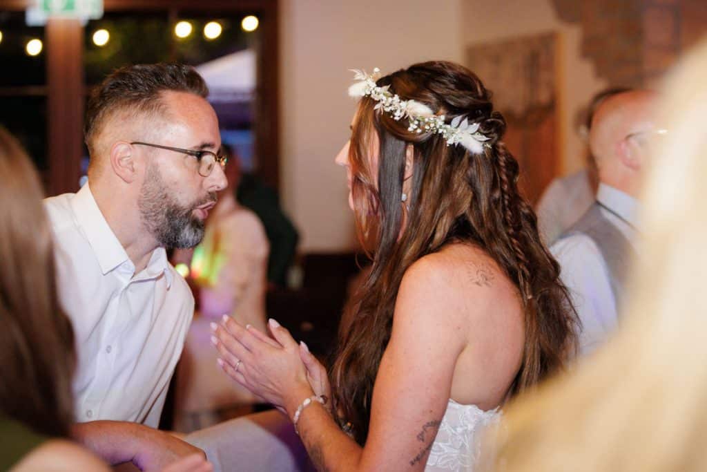 Lebhafte Hochzeitsfeier im Landgut Hochwald in Sonsbeck: Das Brautpaar tanzt ausgelassen mit Familie und Freunden, die Stimmung ist voller Freude und Energie. Die festlich dekorierte Location bietet den perfekten Rahmen für eine unvergessliche Feier, fotografiert vom Hochzeitsfotograf Niederrhein.