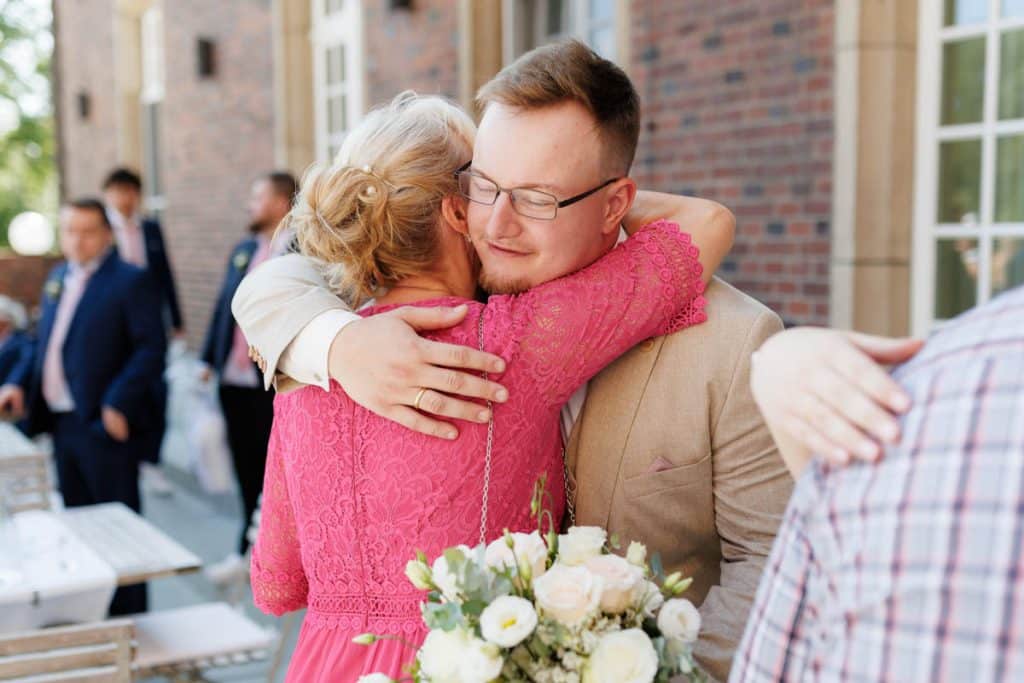 Feierliche Momente nach der Trauung im Schloss Diersfordt in Wesel: Gäste gratulieren dem Brautpaar herzlich, es entstehen weitere Gruppenfotos und beim Sektempfang wird mit Sekt angestoßen. Der Anschnitt der Hochzeitstorte sorgte für zusätzliche emotionale Bilder. Authentisch festgehalten vom Hochzeitsfotograf Wesel.
